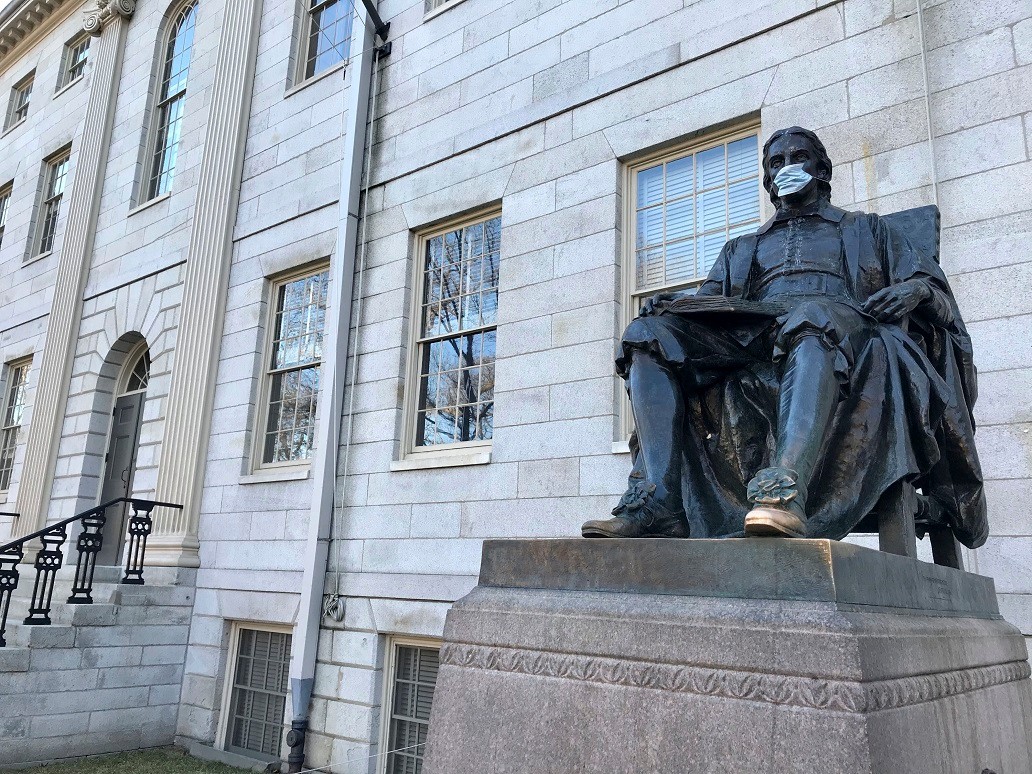 The John Harvard statue at Harvard University, a popular tourist attraction at the campus in Cambridge, Mass, sits adorned with a medical mask as students prepared to leave campus, Saturday, March 14, 2020. The university has asked students to leave by Sunday afternoon and stay home after spring break to prevent the spread of the new coronavirus. For most people, the new coronavirus causes only mild or moderate symptoms, such as fever and cough. For some, especially older adults and people with existing health problems, it can cause more severe illness, including pneumonia. The vast majority of people recover from the new virus. (AP Photo/Collin Binkley)