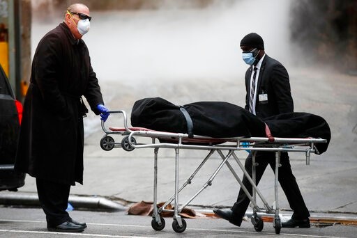 A funeral director wears personal protective equipment due to COVID-19 concerns while collecting a body at The Brooklyn Hospital Center, Thursday, April 9, 2020, in the Brooklyn borough of New York. New York state posted a record-breaking number of coronavirus deaths for a third consecutive day even as a surge of patients in overwhelmed hospitals slowed, while isolation-weary residents were warned Thursday the crisis was far from over. (AP Photo/John Minchillo)