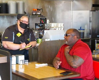 Corey Brooks, right, orders food at a Waffle House restaurant in Savannah, Georgia, on Monday, April 27, 2020. Restaurants statewide were allowed to resume dine-in service with restrictions after a month of being limited to takeout orders because of the coronavirus. (AP Photo/Russ Bynum)