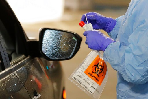 A nurse at a drive up COVID-19 coronavirus testing station, set up by the University of Washington Medical Center, holds a swab used to take a sample from the nose of a person in their car, Friday, March 13, 2020, in Seattle. UW Medicine is conducting drive-thru testing in a hospital parking garage and has screened hundreds of staff members, faculty and trainees for the COVID-19 coronavirus. U.S. hospitals are setting up triage tents, calling doctors out of retirement, guarding their supplies of face masks and making plans to cancel elective surgery as they brace for an expected onslaught of coronavirus patients. (AP Photo/Ted S. Warren)