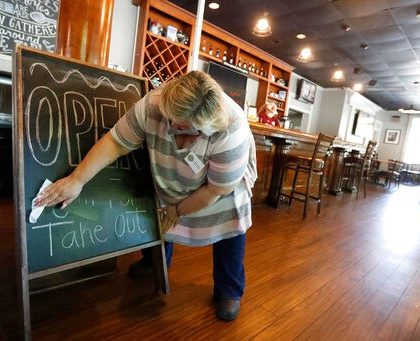 Mary Spoto, general manager of Madison Chop House Grille, changes the sign as she and her staff prepare to shift from take out only to dine-in service Monday, April 27, 2020, in Madison, Ga. Some Georgia restaurants were reopening for limited dine-in service as more restrictions against the coronavirus are loosened in the state. Movie theaters on Monday can welcome customers and limited in-restaurant dining may resume. (AP Photo/John Bazemore)