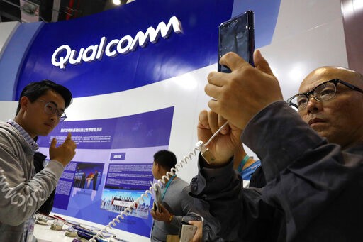 FILE - In this Nov. 6, 2018 file photo, attendees look at the latest technology from Qualcomm at the China International Import Expo in Shanghai. Qualcomm’s stock is tumbling before Wednesday’s market open on May 22, 2019, after a federal judge ruled that the company unlawfully stifled cellphone chip market competition and charged excessive licensing fees.  (AP Photo/Ng Han Guan, File)