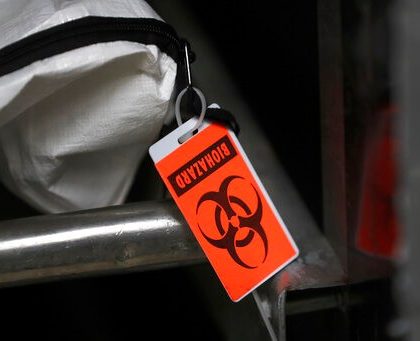 In this Tuesday, May 5, 2020, photo, an orange biohazard tag hangs from a body bag in an isolated refrigerated unit set aside for bodies infected with coronavirus at the Cook County morgue in Chicago. (AP Photo/Charles Rex Arbogast)