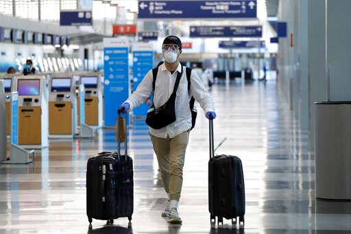 A traveler wears a mask and protective goggles as he walks through Terminal 3 at O'Hare International Airport Tuesday, June 16, 2020, in Chicago. Beginning June 16 at American Airlines and June 18 at United Airlines, all passengers and crew members will be required to wear masks to prevent the spread of COVID-19 pandemic. (AP Photo/Nam Y. Huh)