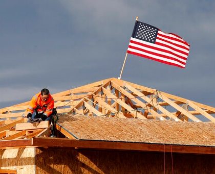 The American flag flutters in the wind as work is done on the roof of a building under construction in Sacramento, Calif., Tuesday, March 31, 2020. While most Californian's have spent more than a week under a mandatory stay-at-home order, because of the coronavirus, construction work is among the jobs exempt as part of the "essential infrastructure." (AP Photo/Rich Pedroncelli)