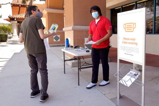 Staples employee Mark Amezcua, center, assists a customer during the coronavirus outbreak, Thursday, May 7, 2020, in Westlake Village, Calif. California Gov. Gavin Newsom has issued the broadest loosening of his stay-at-home order so far, allowing some retailers to reopen but not have customers in stores. (AP Photo/Mark J. Terrill)