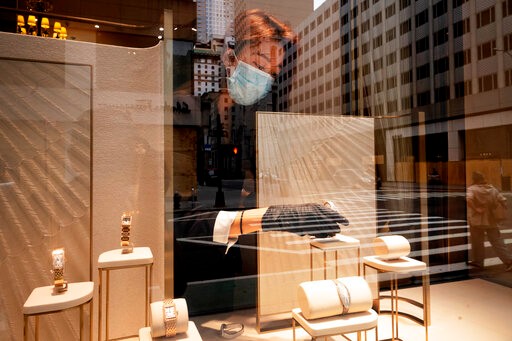 A Cartier employee places a watch in a window display, Thursday, June 11, 2020, in New York's Fifth Avenue shopping district. The jeweler is open for pickup only. (AP Photo/Mark Lennihan)