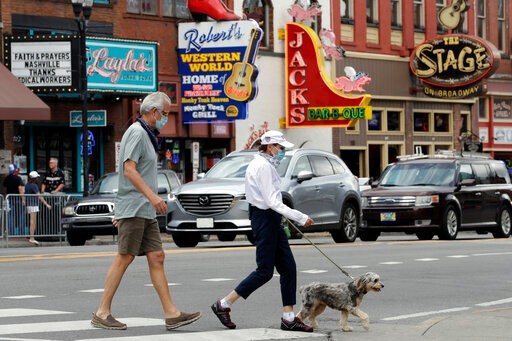 People wear masks as they cross Broadway Tuesday, June 30, 2020, in Nashville, Tenn. The Nashville Health Department has put in place a mask mandate to help battle the spread of the coronavirus. (AP Photo/Mark Humphrey)