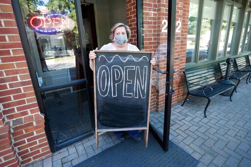Mary Spoto, general manager of Madison Chop House Grille, places a sign outside the restaurant as she and her staff prepare to shift from take out only to dine-in service Monday, April 27, 2020, in Madison, Ga. Some Georgia restaurants were reopening for limited dine-in service as more restrictions against the coronavirus are loosened in the state. Movie theaters on Monday can welcome customers and limited in-restaurant dining may resume. (AP Photo/John Bazemore)