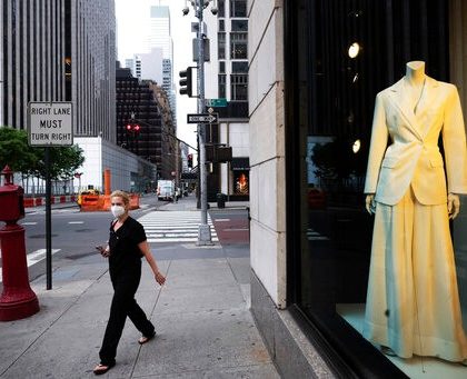 A woman wearing a mask walks by Bergdorf Goodman store, Thursday, June 11, 2020, in New York's Fifth Avenue shopping district. The luxury goods store is open for curbside pickup. (AP Photo/Mark Lennihan)