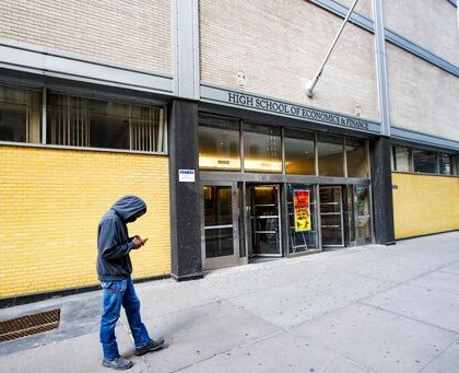 A pedestrian wears a face mask while standing outside the High School of Economics & Finance closed due to coronavirus concerns, Monday, March 16, 2020, in New York. New York leaders took a series of unprecedented steps Sunday to slow the spread of the coronavirus, including canceling schools and extinguishing most nightlife in New York City. (AP Photo/John Minchillo)