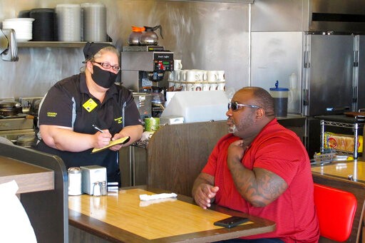 Corey Brooks, right, orders food at a Waffle House restaurant in Savannah, Georgia, on Monday, April 27, 2020. Restaurants statewide were allowed to resume dine-in service with restrictions after a month of being limited to takeout orders because of the coronavirus. (AP Photo/Russ Bynum)