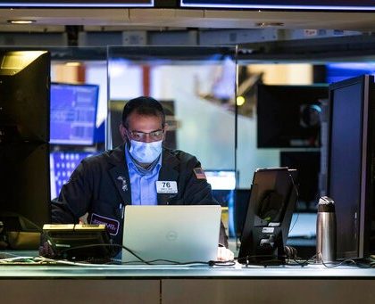 In this photo provided by the New York Stock Exchange, trader Aman Patel wears a protective face mask as he works on the partially reopened trading floor, Tuesday, May 26, 2020. Stocks surged on Wall Street in afternoon trading Tuesday, driving the S&P 500 to its highest level in nearly three months, as hopes for economic recovery overshadow worries about the coronavirus pandemic. (Colin Zimmer/New York Stock Exchange via AP)