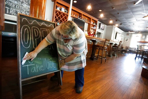 Mary Spoto, general manager of Madison Chop House Grille, changes the sign as she and her staff prepare to shift from take out only to dine-in service Monday, April 27, 2020, in Madison, Ga. Some Georgia restaurants were reopening for limited dine-in service as more restrictions against the coronavirus are loosened in the state. Movie theaters on Monday can welcome customers and limited in-restaurant dining may resume. (AP Photo/John Bazemore)