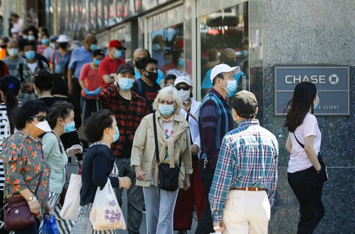 Patrons wearing protective masks wait to enter a Chase bank location, Monday, June 8, 2020, in the Flushing section of the Queens borough of New York. After three bleak months, New York City will try to turn a page when it begins reopening Monday after getting hit first by the coronavirus, then an outpouring of rage over racism and police brutality. (AP Photo/Frank Franklin II)