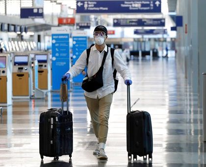 A traveler wears a mask and protective goggles as he walks through Terminal 3 at O'Hare International Airport Tuesday, June 16, 2020, in Chicago. Beginning June 16 at American Airlines and June 18 at United Airlines, all passengers and crew members will be required to wear masks to prevent the spread of COVID-19 pandemic. (AP Photo/Nam Y. Huh)