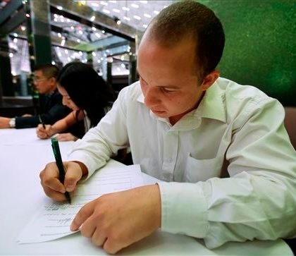 In this Monday, Oct. 6, 2014 photo, Jonathan Alsina, 25, of Miami, fills out paperwork before being interviewed during a job fair at Fontainebleau Miami Beach in Miami Beach, Fla. The Labor Department releases weekly jobless claims for the week of Oct. 27 on Thursday, Nov. 6, 2014. (AP Photo/Wilfredo Lee)