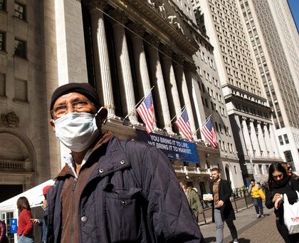 A man wears a mask as he passes the New York Stock Exchange, Monday, March 9, 2020. The dizzying action in financial markets escalated Monday as stocks moved closer to a bear market and oil prices fell the most since 2008. (AP Photo/Mark Lennihan)