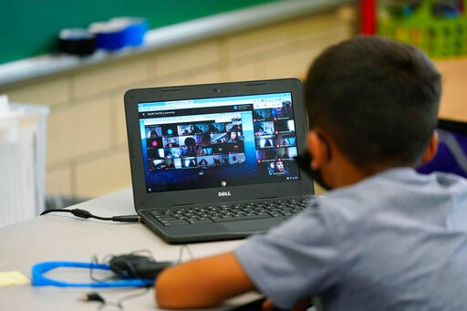Justin Castilla works on a laptop in a classroom in Newlon Elementary School early Tuesday, Aug. 25, 2020, which is one of 55 Discovery Link sites set up by Denver Public Schools where students are participating in remote learning in this time of the new coronavirus from a school in Denver. (AP Photo/David Zalubowski)