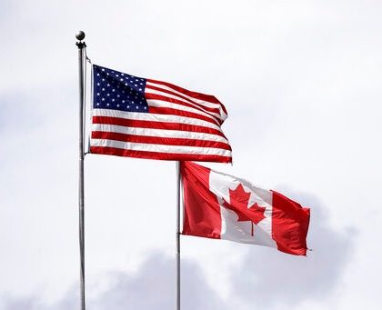 In this photo taken Sunday, May 17, 2020, U.S. and Canadian flags fly atop the Peace Arch at Peace Arch Historical State Park on the border with Canada, where people can walk freely between the two countries at an otherwise closed border, in Blaine, Wash. Canada and the U.S. have agreed to extend their agreement to keep the border closed to non-essential travel to June 21 during the coronavirus pandemic. The restrictions were announced on March 18, were extended in April and now extended by another 30 days. (AP Photo/Elaine Thompson)